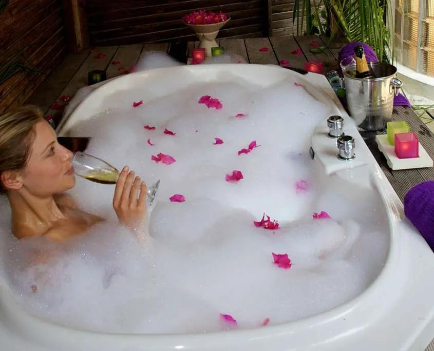 In-villa jacuzzi bath on a Jacuzzi Beach Villa's deck, filled and set with candles and rose petals