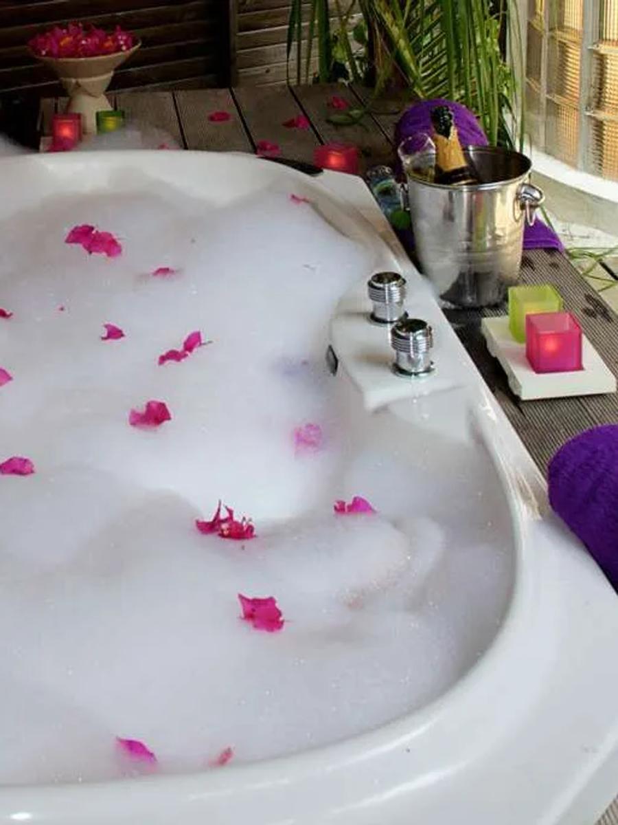 In-villa jacuzzi bath on a Jacuzzi Beach Villa's deck, filled and set with candles and rose petals