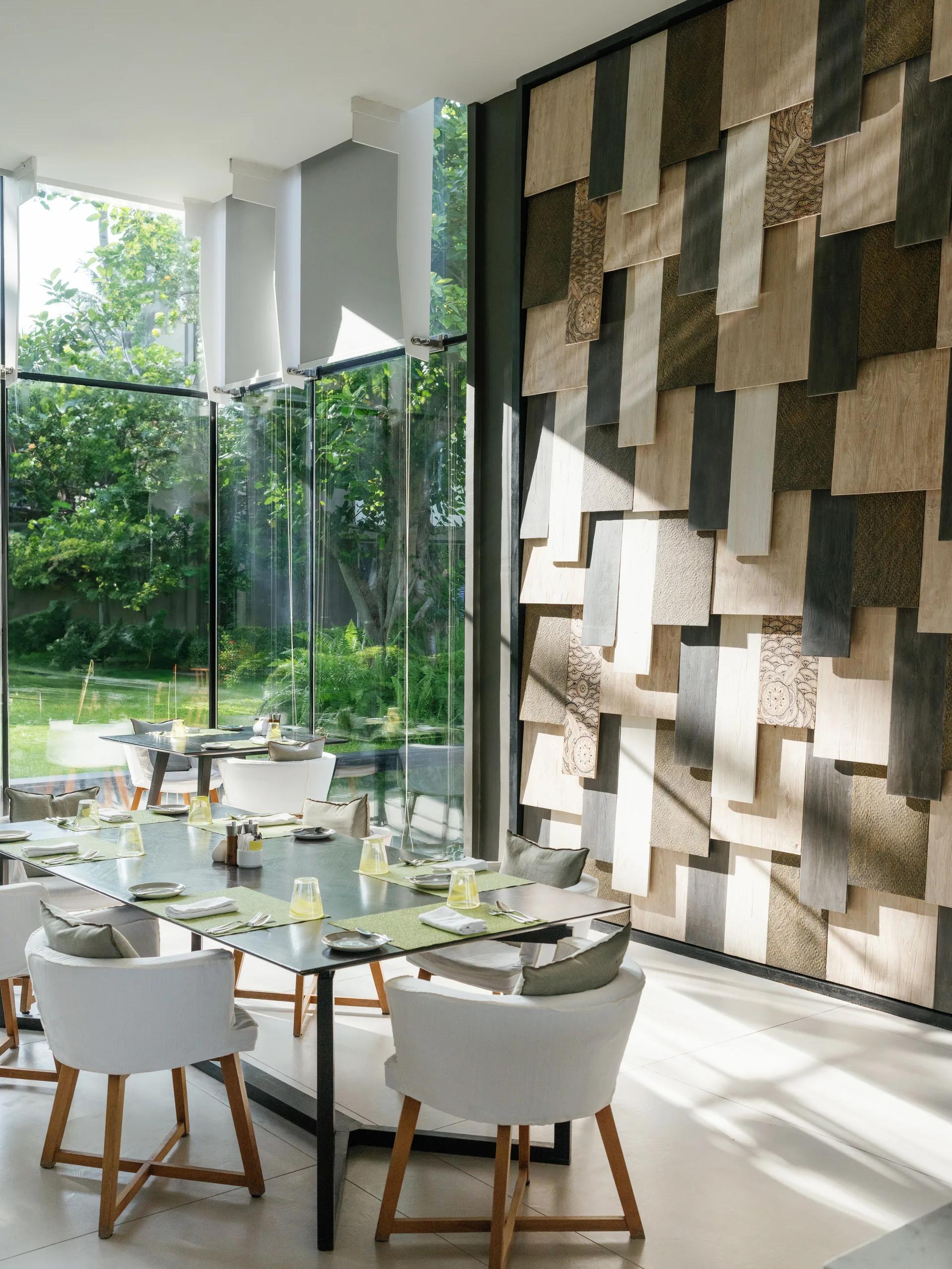 The White's dining room, tables set beneath a geometric wood-shingle wall with floor-to-ceiling windows onto the garden