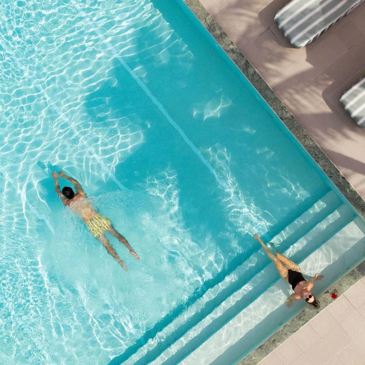 A guest swimming in the infinity pool at West Beach Bar, OBLU SELECT Lobigili, loungers on the deck alongside