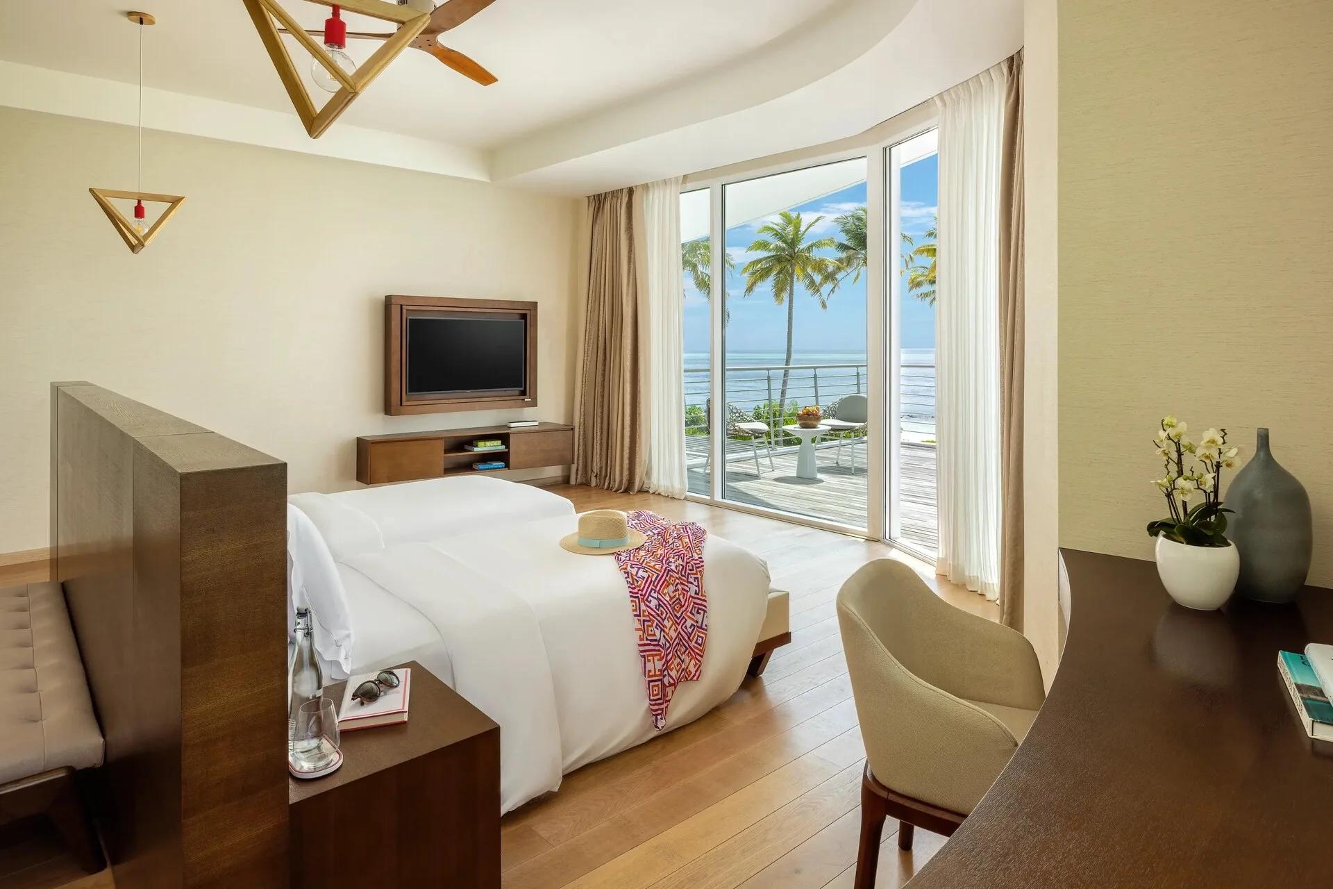 A twin bedroom in a Three Bedroom Beach Retreat, glass doors opening onto a private terrace and the sea