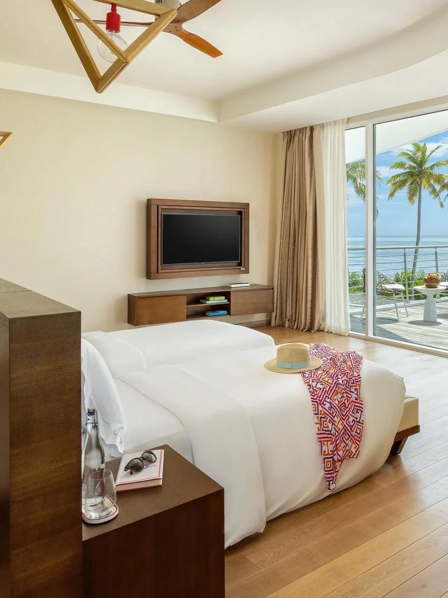 A twin bedroom in a Three Bedroom Beach Retreat, glass doors opening onto a private terrace and the sea