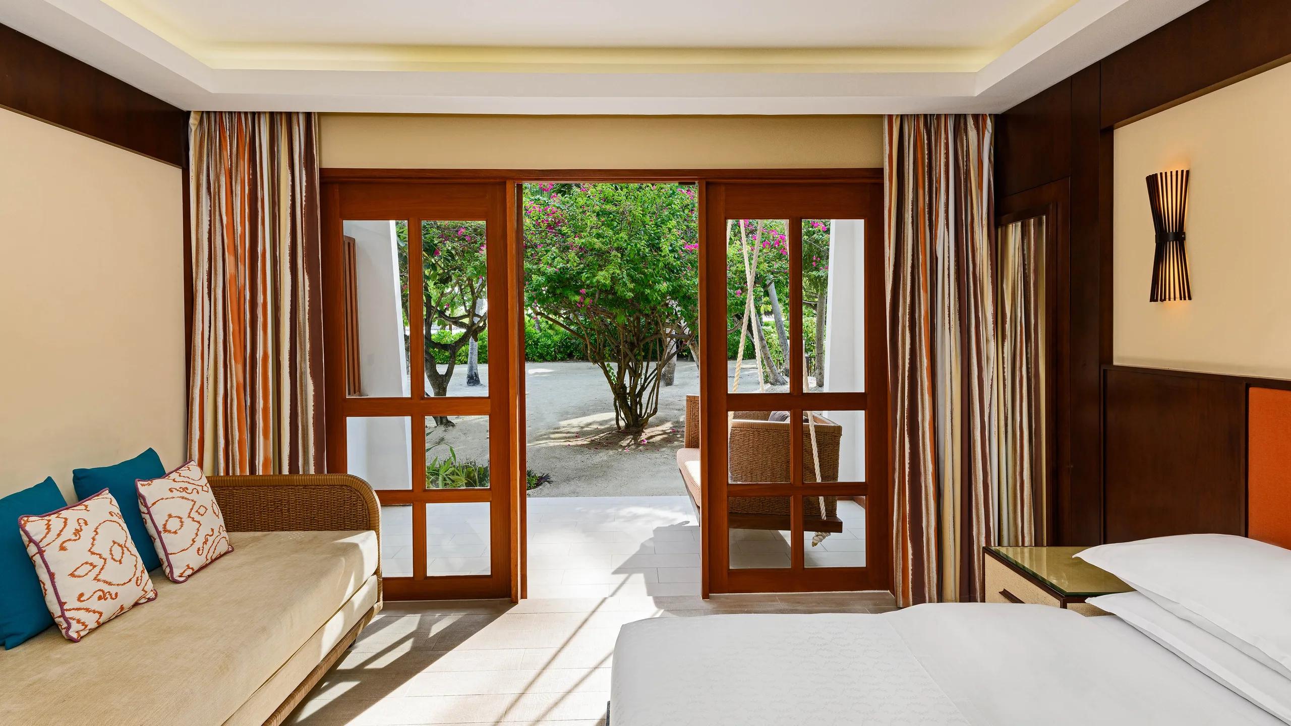 Deluxe Guest Room bedroom opening onto a private garden terrace with a hanging daybed swing