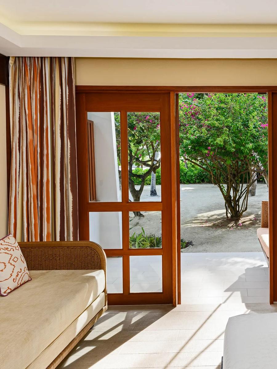 Deluxe Guest Room bedroom opening onto a private garden terrace with a hanging daybed swing
