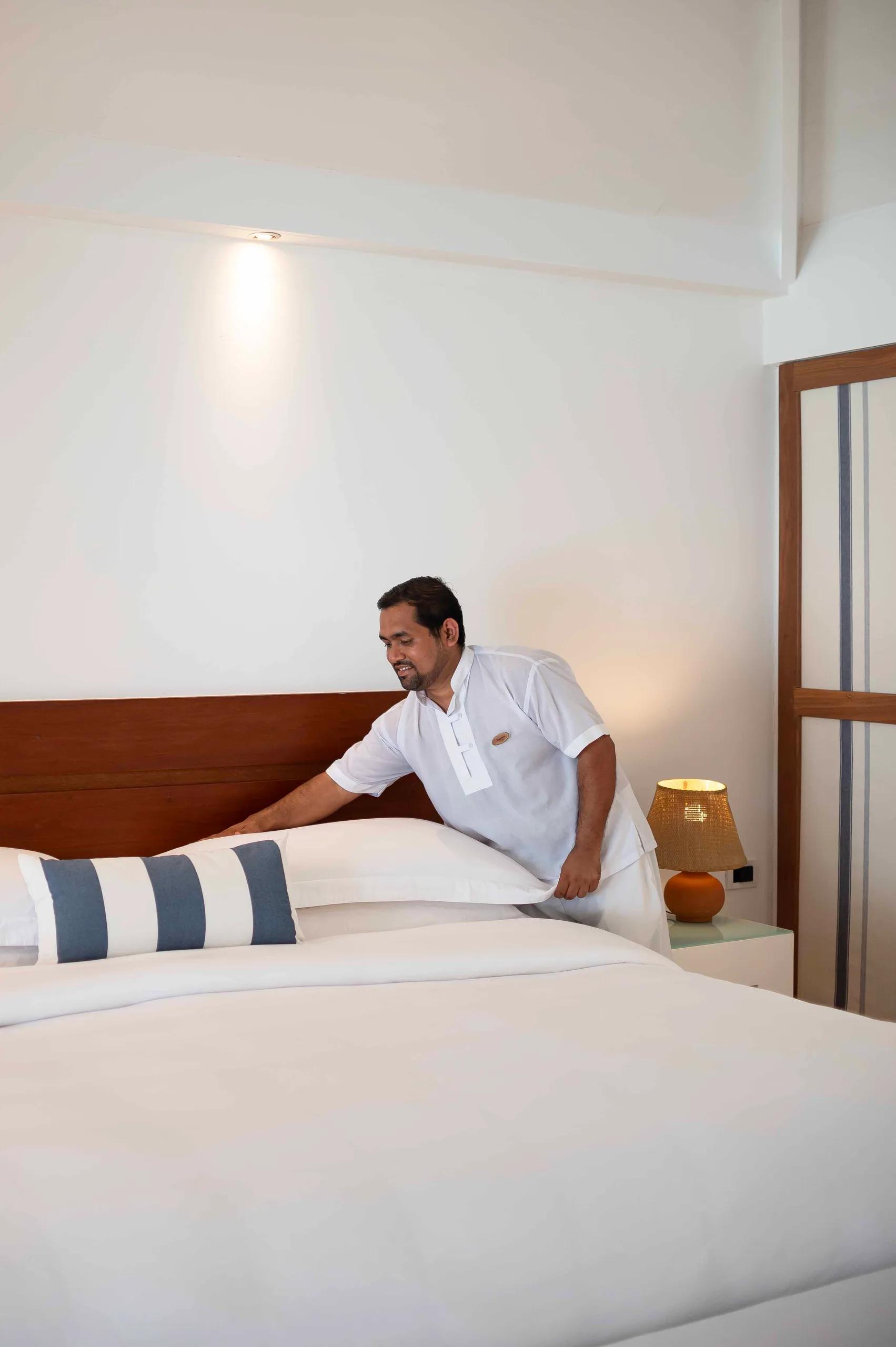 A member of the housekeeping team turning down a bed at Diamonds Athuruga