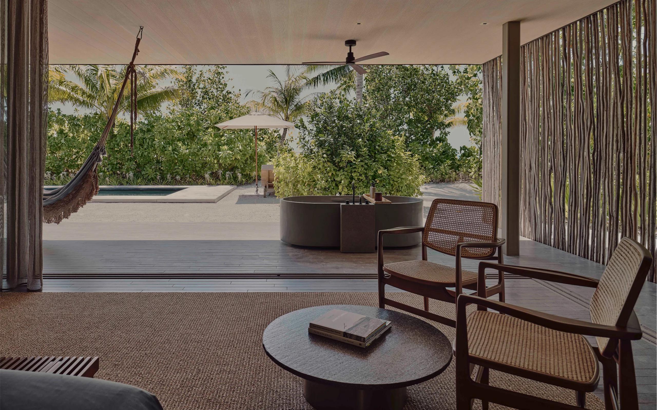 A shaded terrace, outdoor tub, and private pool at a Two-Bedroom Beach Pool Villa, framed by tropical planting