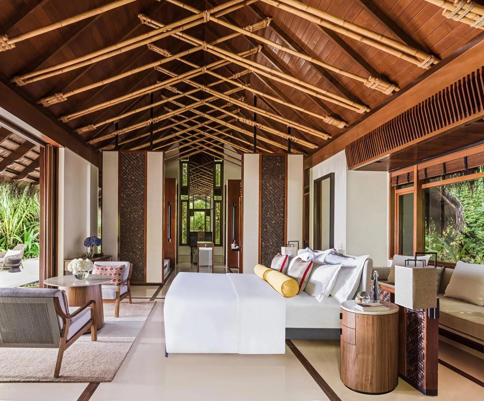 The bedroom of a Beach Villa at One&Only Reethi Rah, glass doors open to the garden and pool