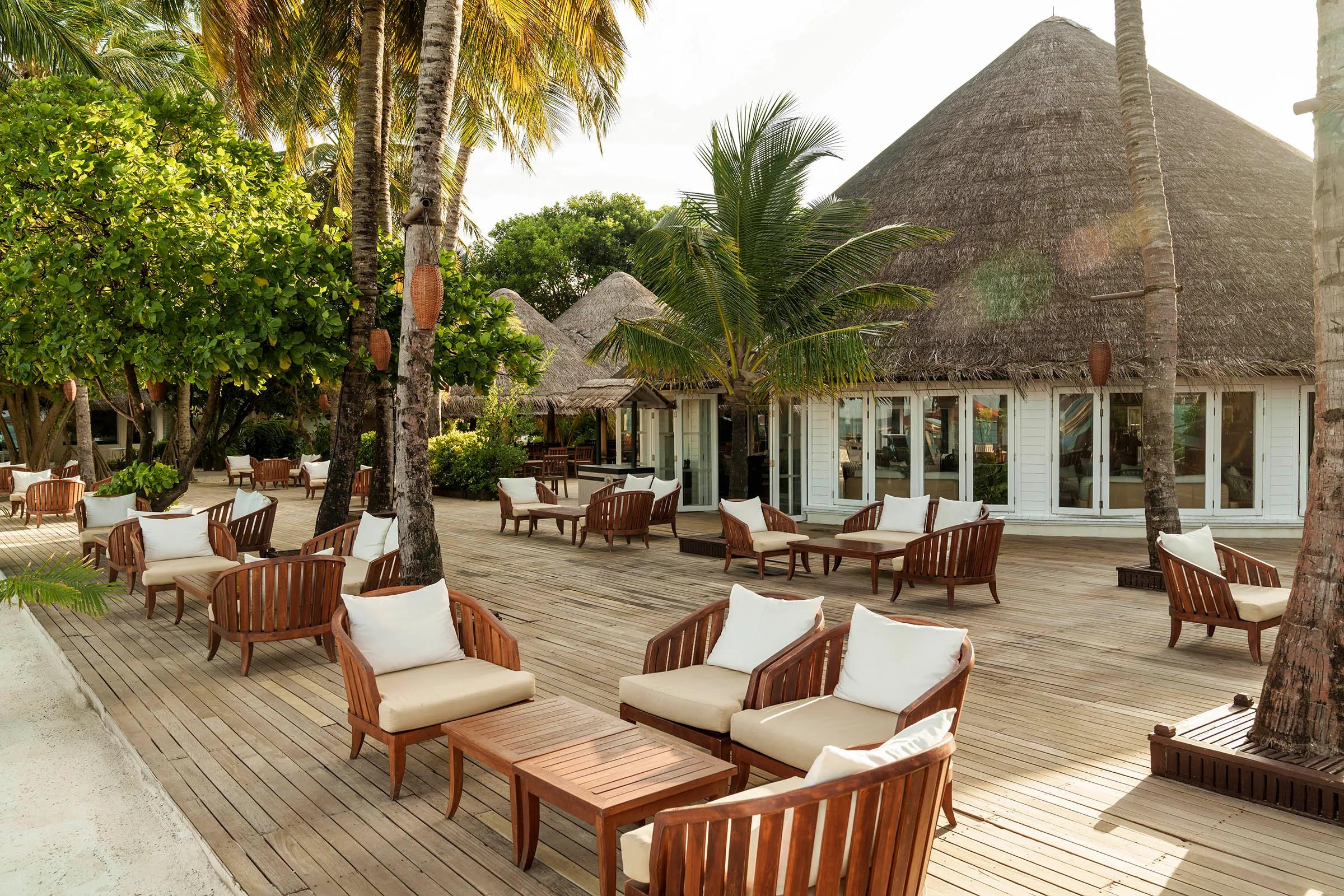 A thatched-roof beach lounge and dining deck open to the ocean at Waters Edge