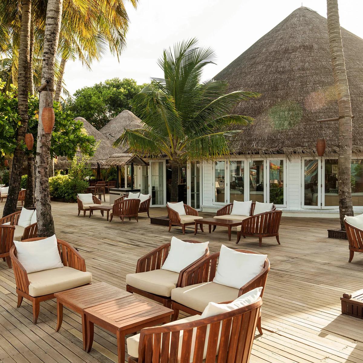 A thatched-roof beach lounge and dining deck open to the ocean at Waters Edge