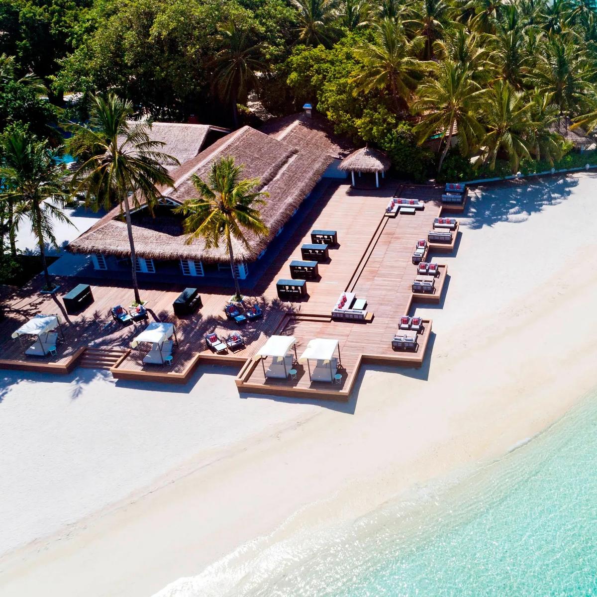 Aerial view of Anchorage's beachfront deck, sun loungers and a thatched pavilion set where the island narrows toward the lagoon