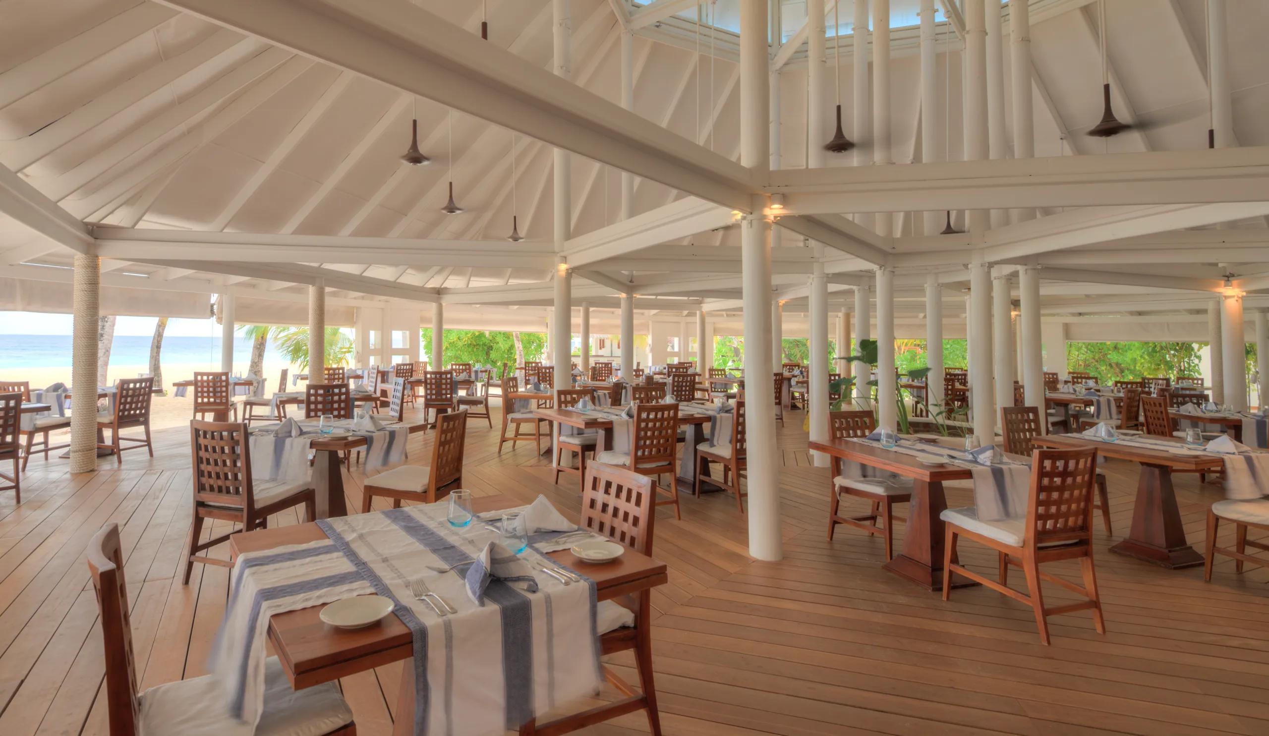 Open-air interior of Maakeyn Buffet Restaurant at Diamonds Athuruga, beach visible beyond