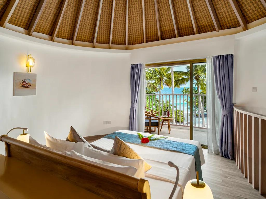 The upper-level bedroom of a Premium Beach Villa, twin daybeds facing a private balcony over the trees toward the sea