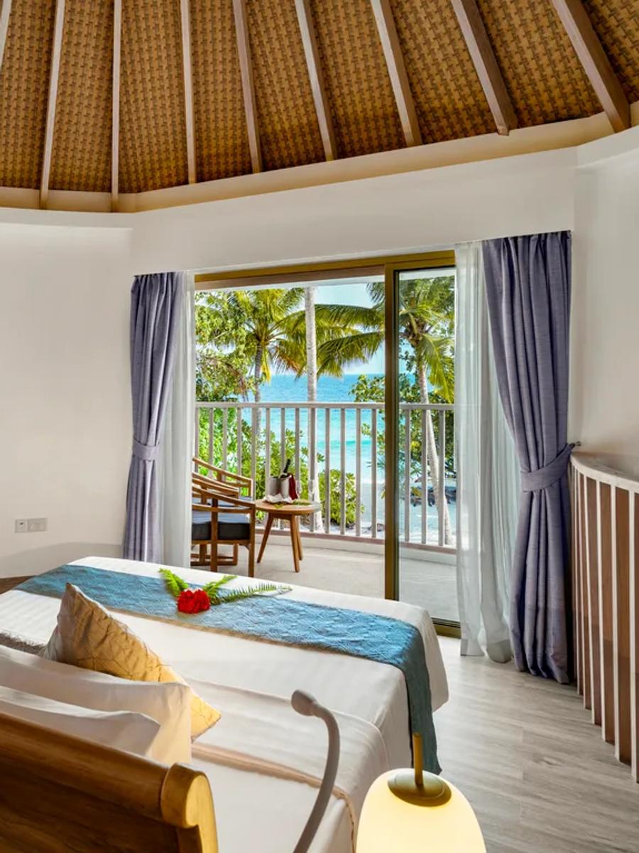 The upper-level bedroom of a Premium Beach Villa, twin daybeds facing a private balcony over the trees toward the sea