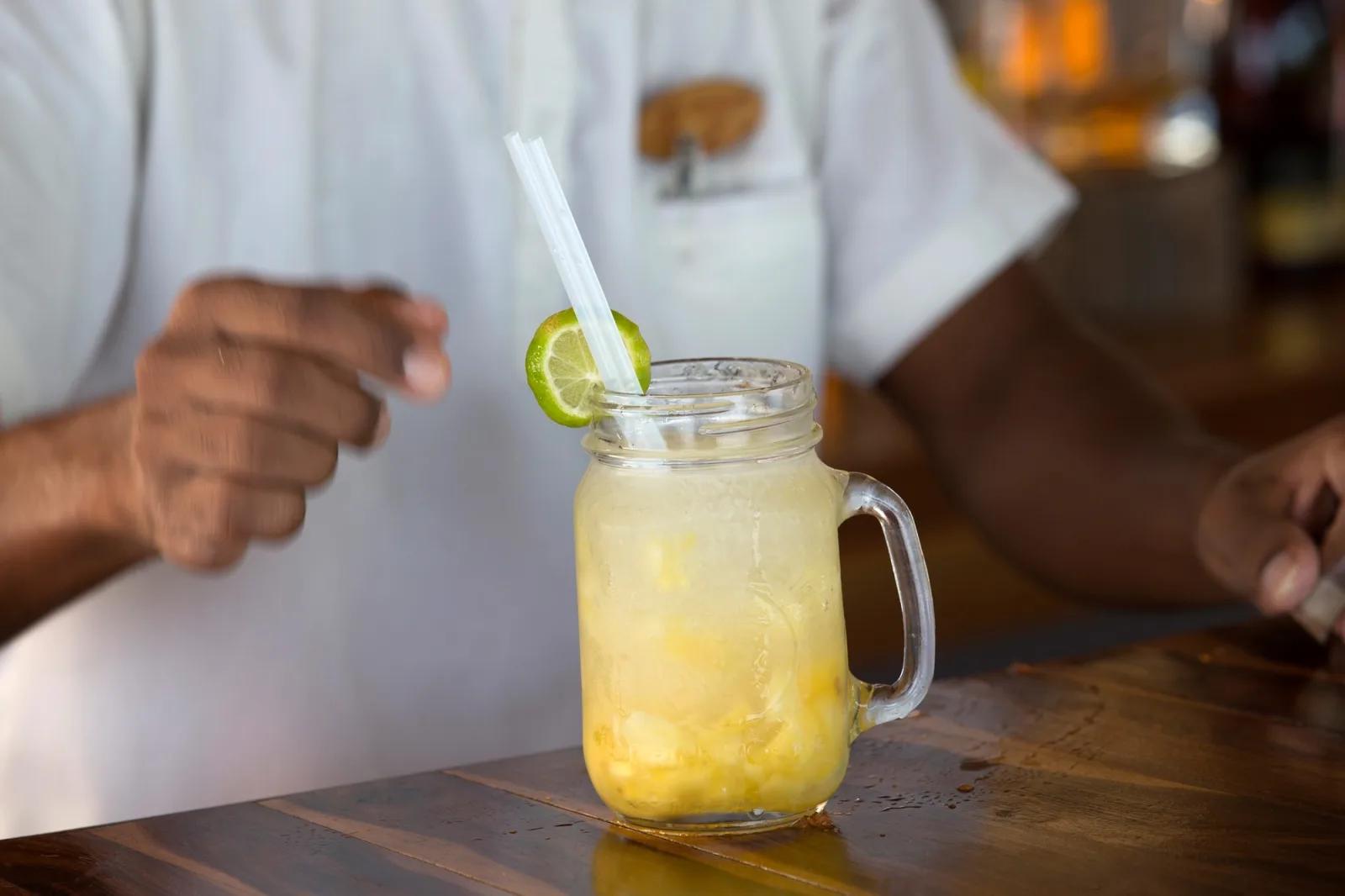 A pineapple cocktail in a mason-jar glass, garnished with lime, served at Beach Bar
