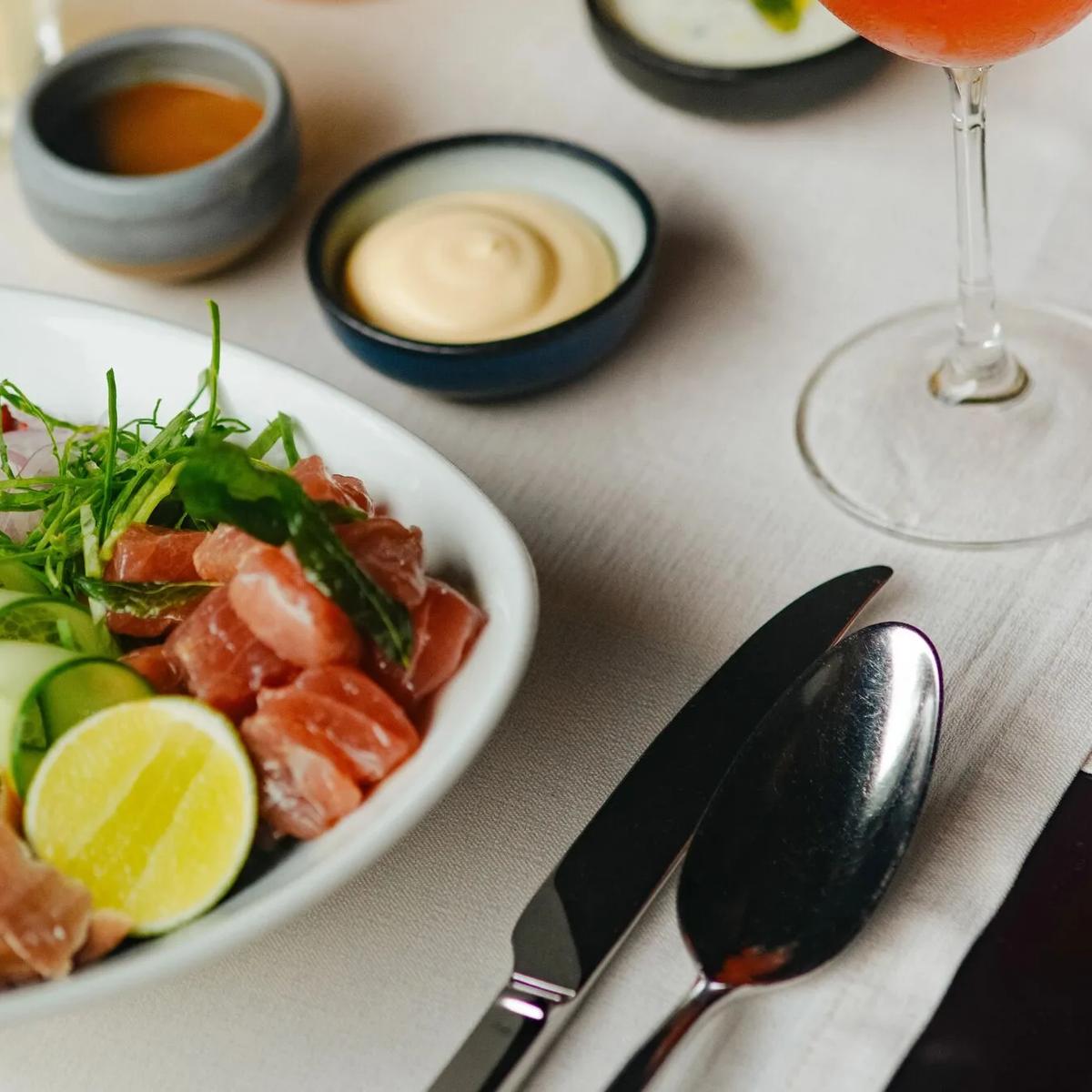 A tuna poke bowl with pickled vegetables, lime and dipping sauces, plated at Mura Bar