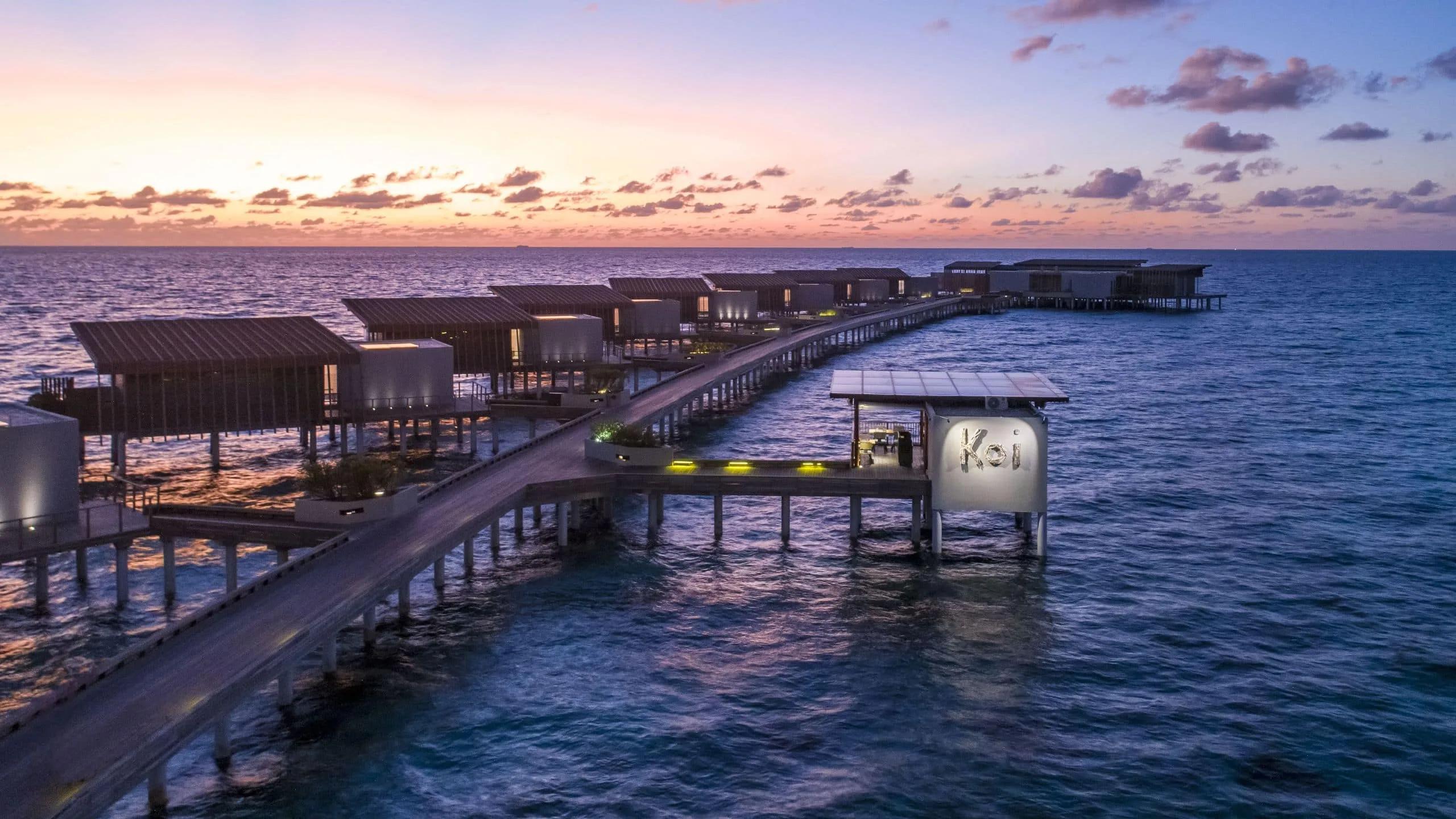 Koi at The Drift, an overwater restaurant lit at the end of a long jetty at dusk