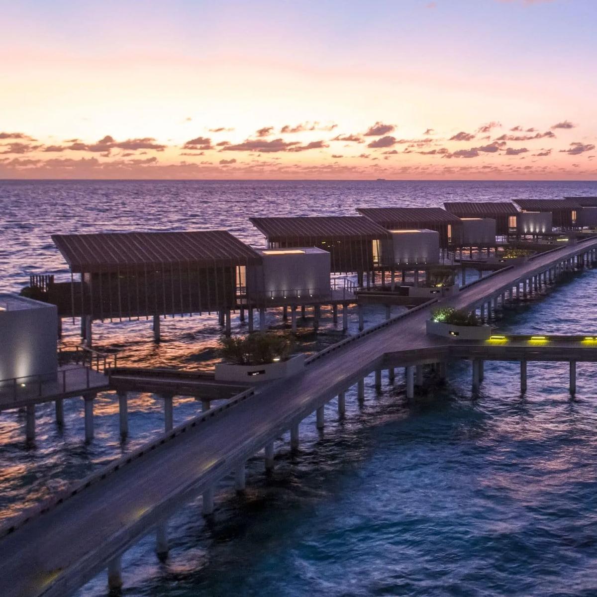 Koi at The Drift, its lit signage visible at the end of the overwater jetty at dusk