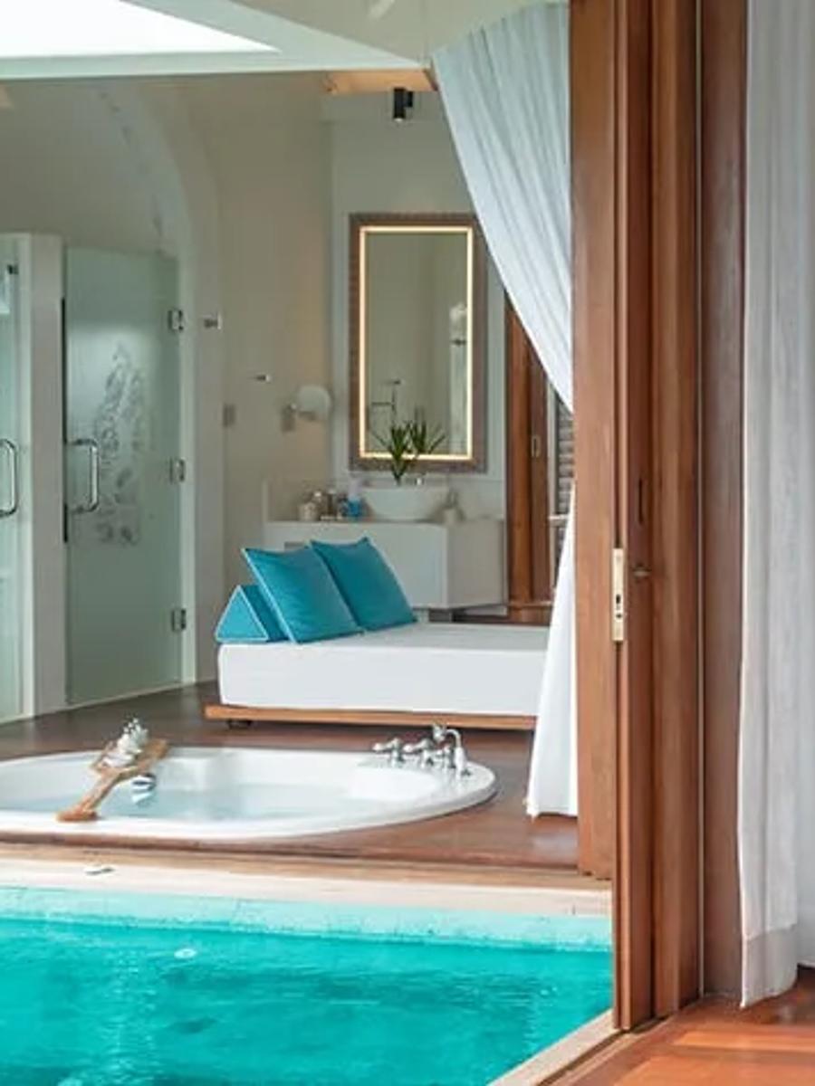 Bedroom of a Sunset Over Water Pool Villa at Anantara Kihavah, with a pool and bathroom view