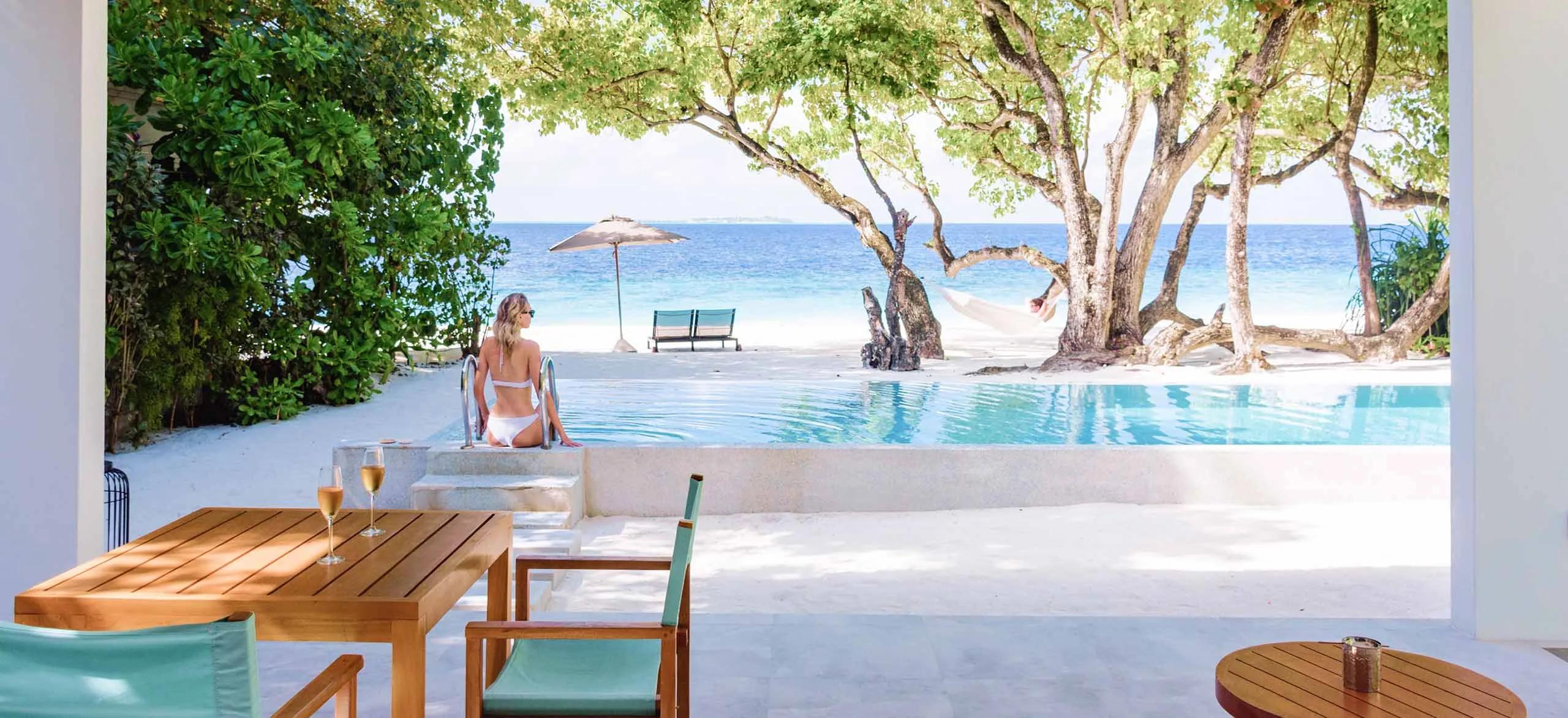 A Beach Pool Villa at Amilla, its private pool and lounge chairs set beneath a canopy of trees on the beach