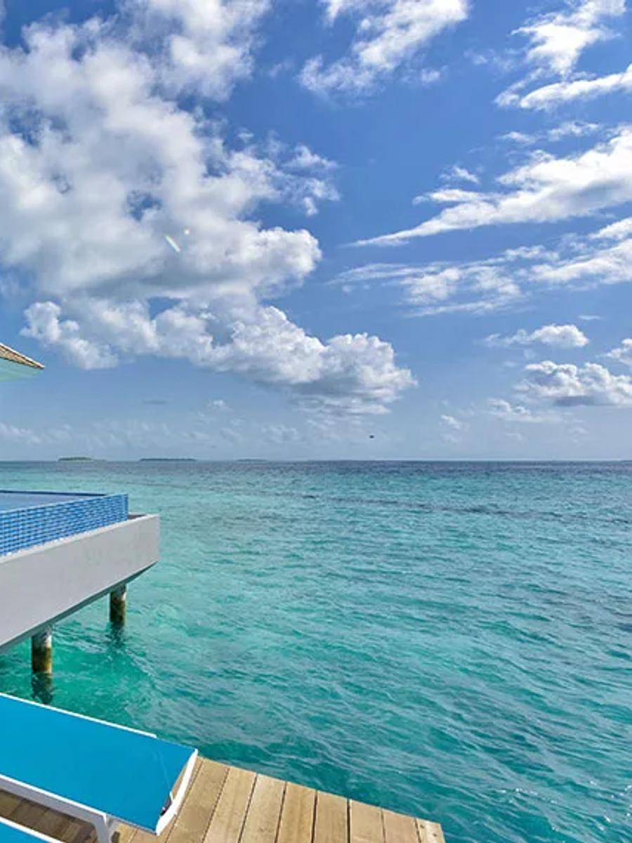 An overwater pool villa's private infinity-edge pool and sun loungers, built out over the lagoon