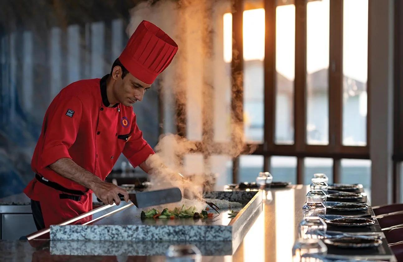 A chef prepares vegetables tableside at the Teppanyaki Grill's hotplate