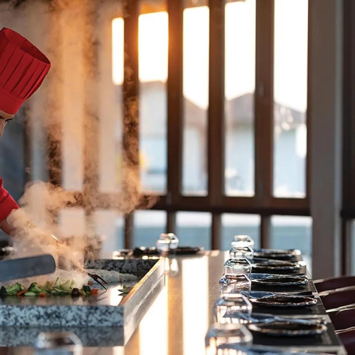 A chef prepares vegetables tableside at the Teppanyaki Grill's hotplate