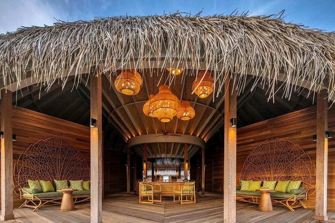 A round, thatched-roof pavilion at Solasta Spa, with green cushioned daybeds either side of a central bar.