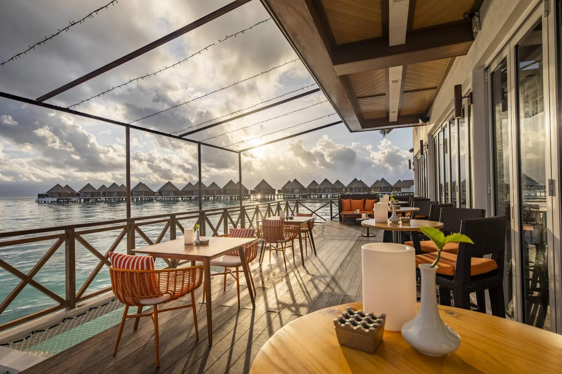 Vista's overwater dining deck at Mercure Maldives Kooddoo Resort, set for sunset