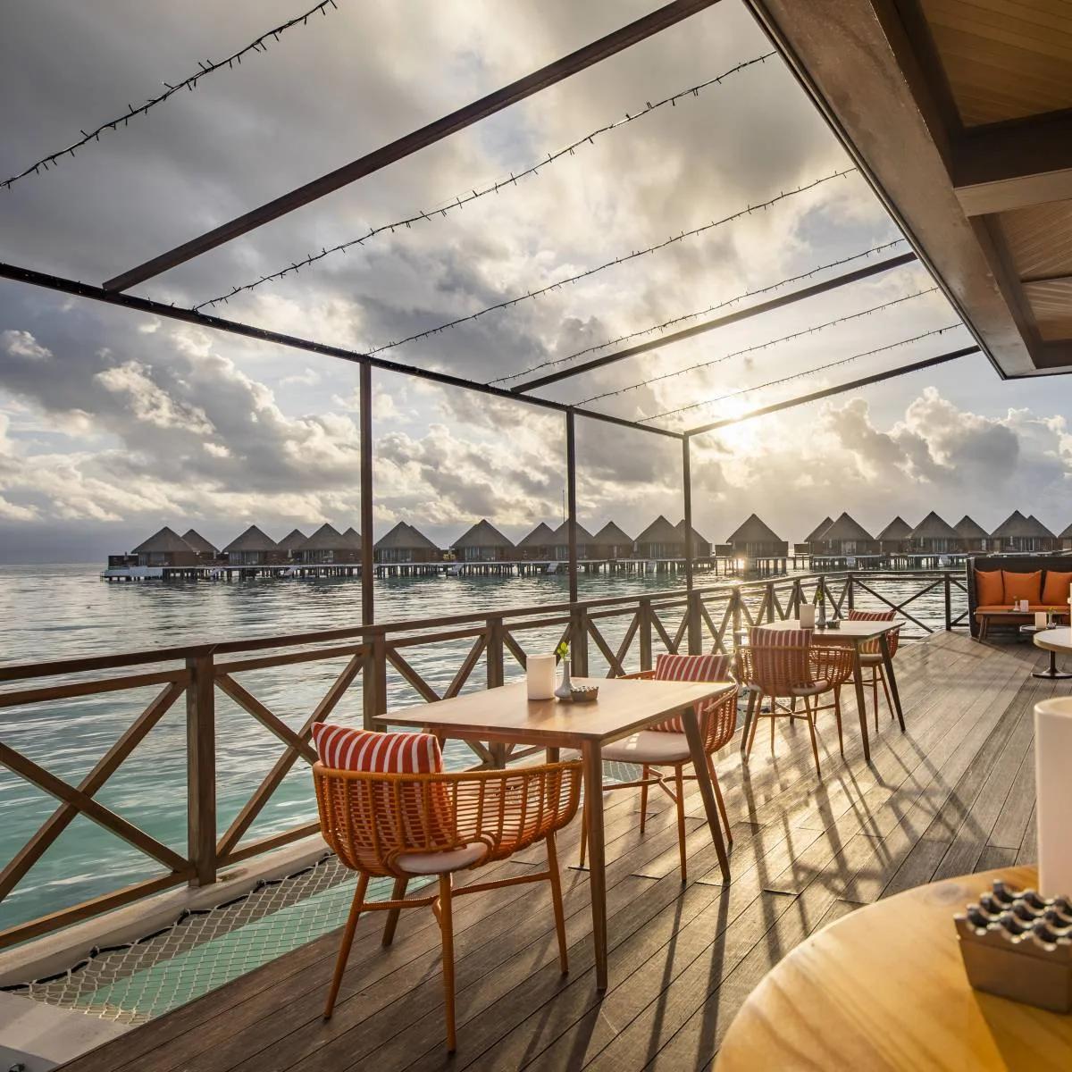 Vista's overwater dining deck at Mercure Maldives Kooddoo Resort, set for sunset