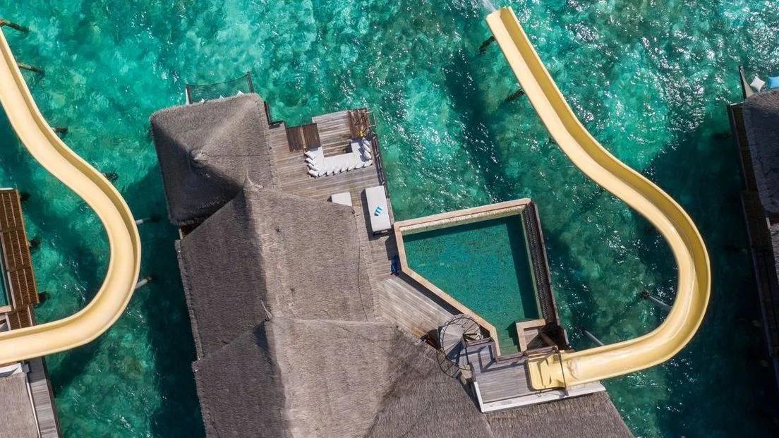 Directly overhead view of an Ocean Pool Suite with Slide's private infinity pool and yellow slide curving into the lagoon
