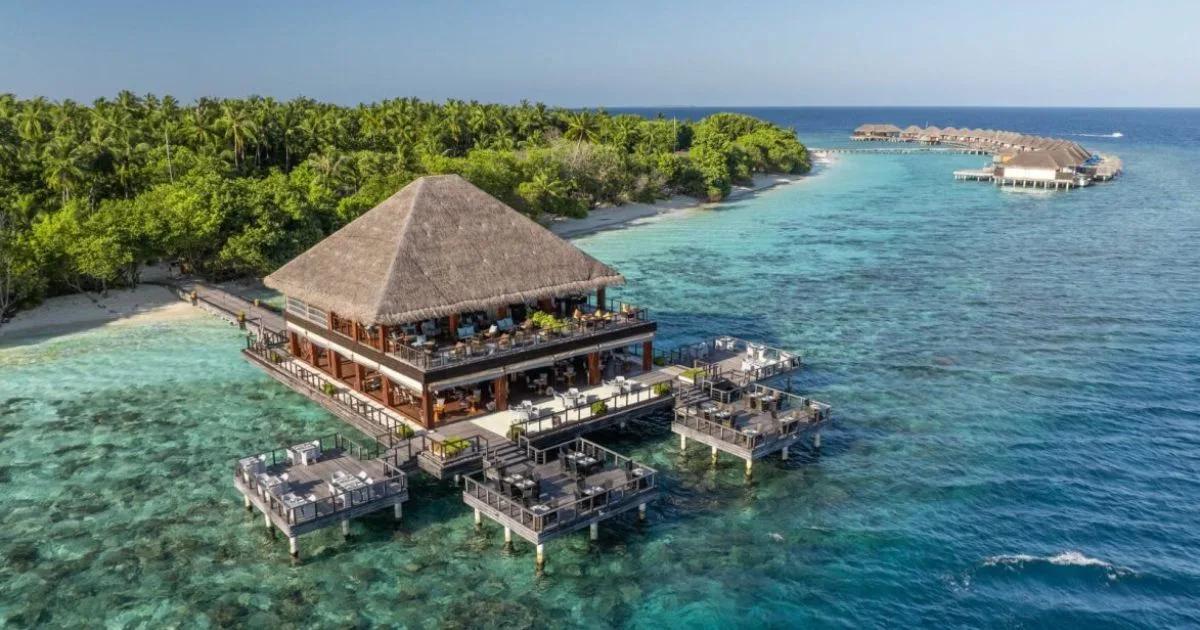An aerial view of Benjarong, Dusit Thani Maldives' overwater Thai fine-dining restaurant, connected to the island by a wooden walkway