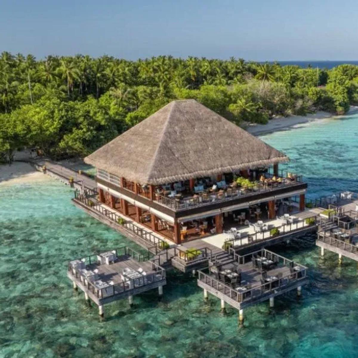 The overwater dining terrace at Benjarong, Dusit Thani Maldives' Thai fine-dining restaurant, connected to the island by a wooden walkway