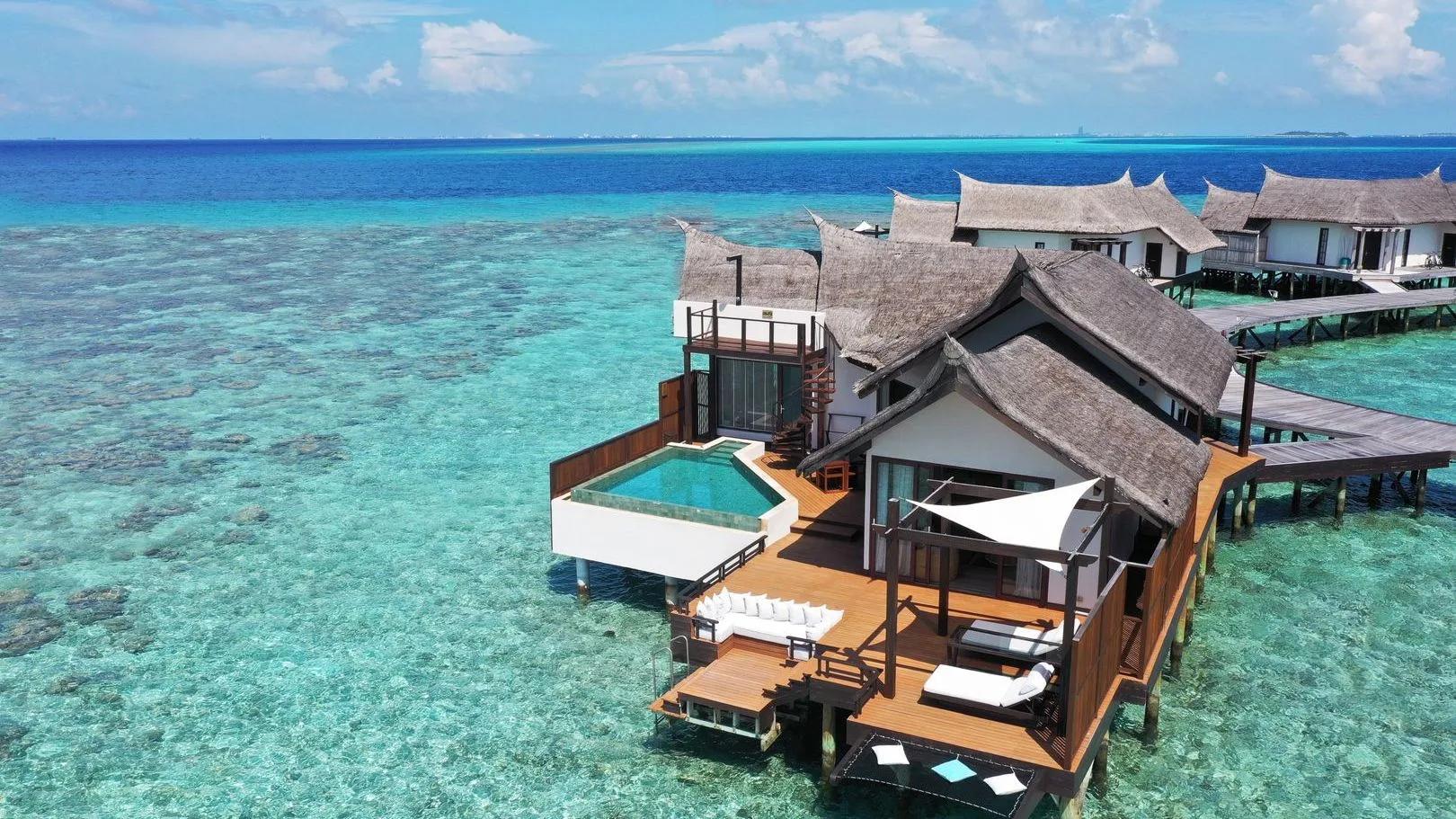 An Ocean Pool Suite's private infinity pool and deck extending over the lagoon, with an overwater hammock alongside