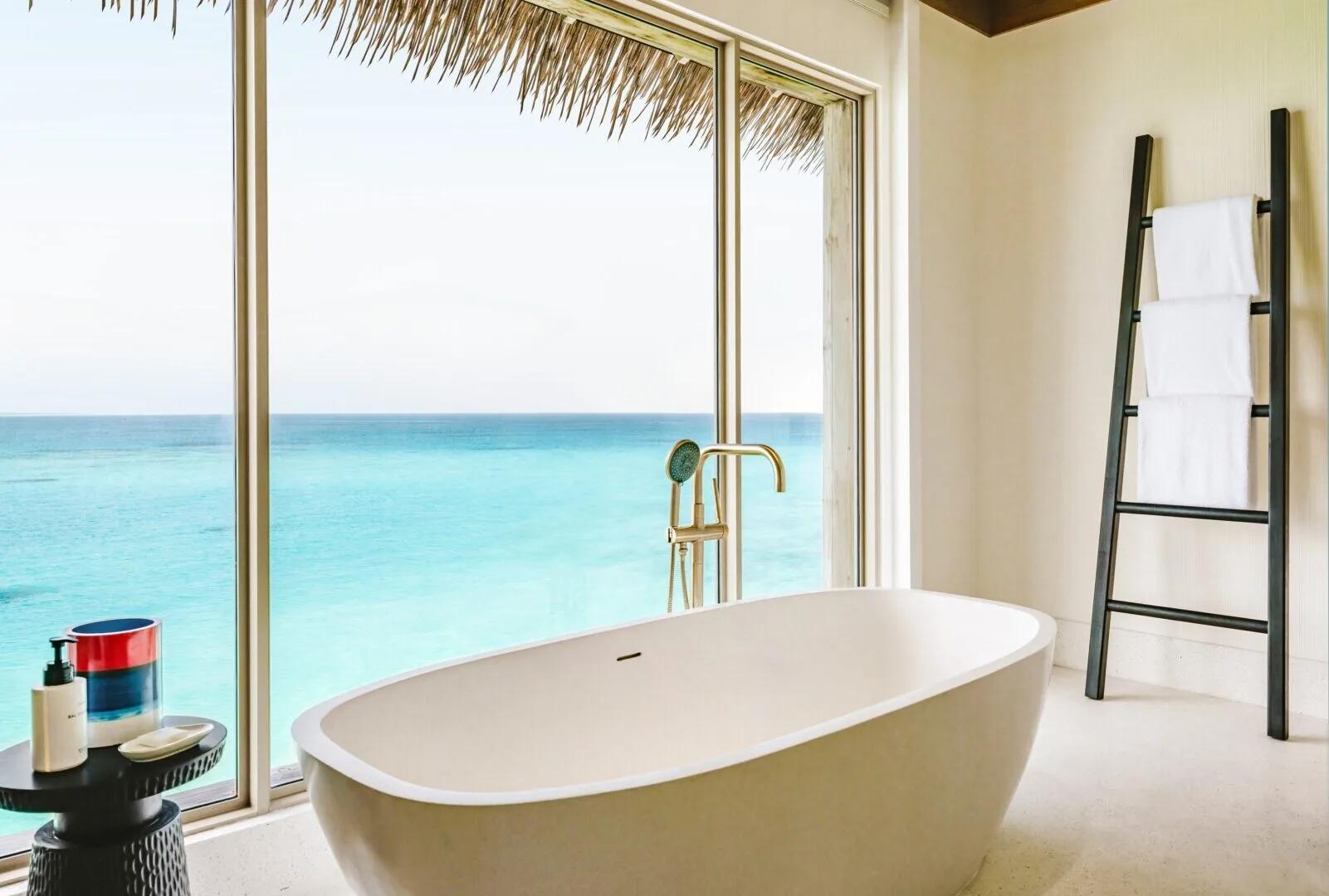 The bathroom of a One-Bedroom Sunset Lagoon Pool Villa, a freestanding tub facing the lagoon
