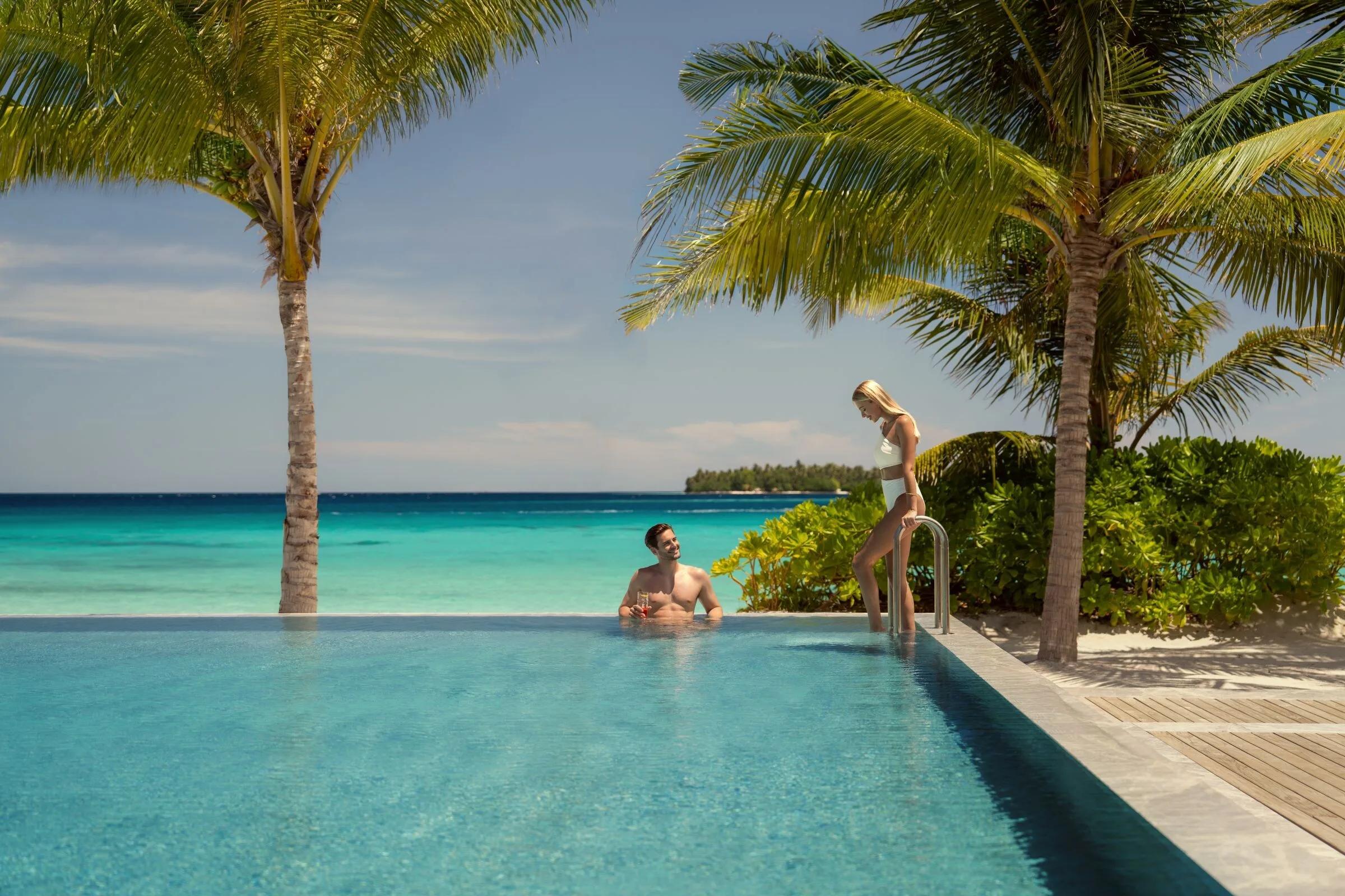 The resort's infinity pool meeting the lagoon at the horizon