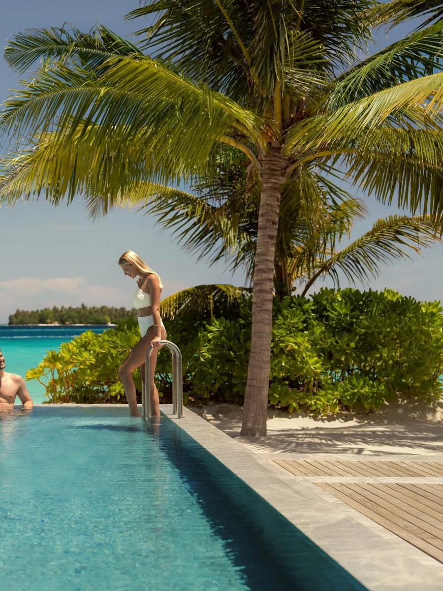 The resort's infinity pool meeting the lagoon at the horizon