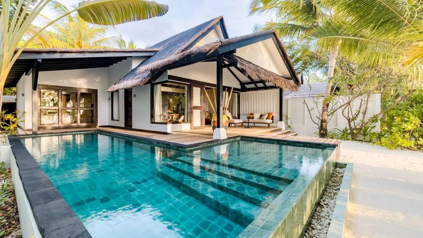 The Earth Pool Pavilion's thatched roofline over a long private pool, garden path leading to the entrance
