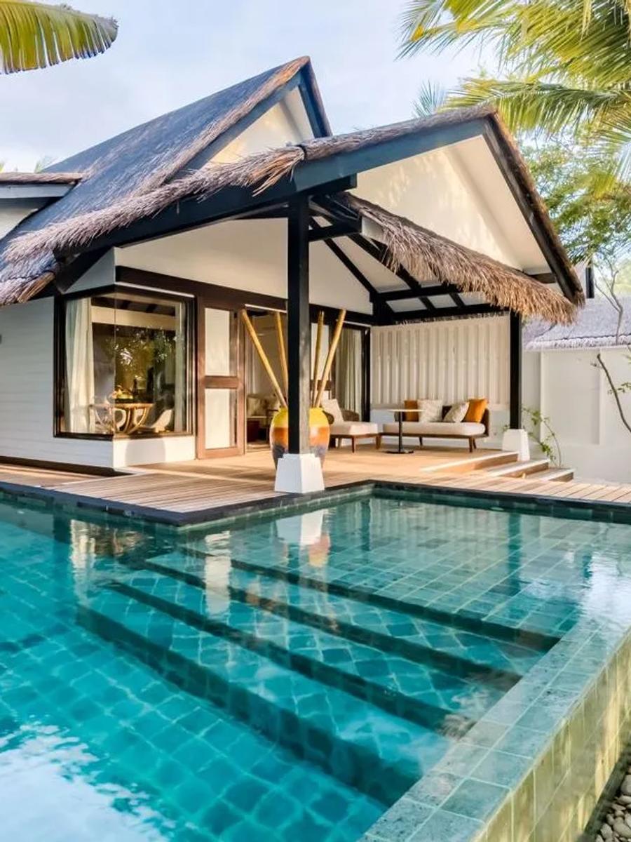The Earth Pool Pavilion's thatched roofline over a long private pool, garden path leading to the entrance