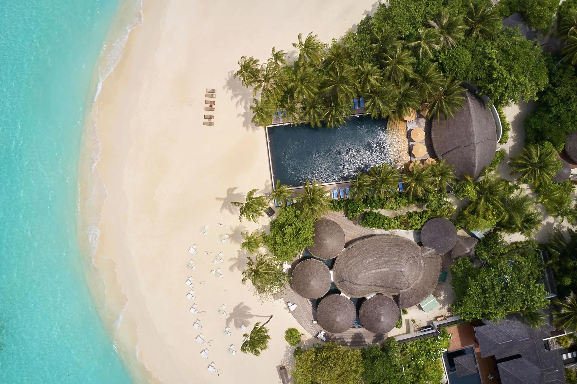 Aerial view of the adults-only Reflections pool, with an infinity edge, thatched bar structures and beach loungers