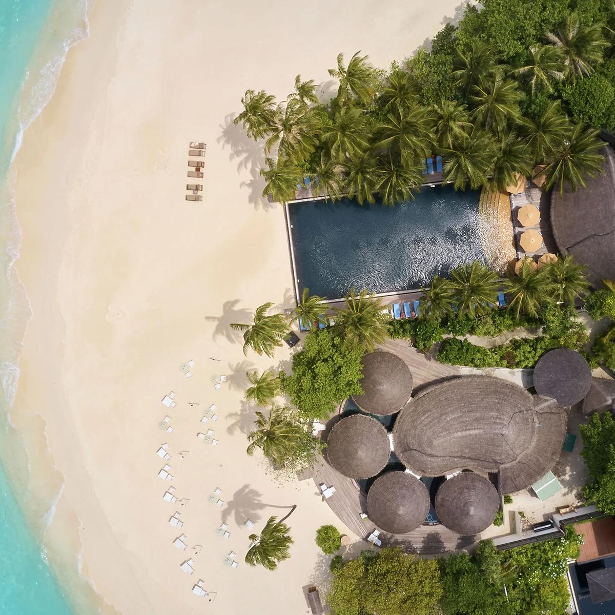 Aerial view of the adults-only Reflections pool, with an infinity edge, thatched bar structures and beach loungers