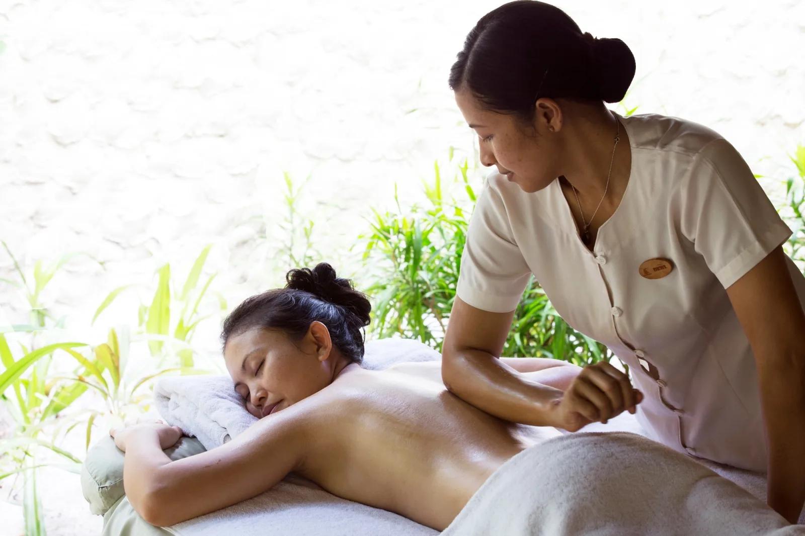 A massage in progress on an open-air treatment platform at Coco Spa, surrounded by greenery