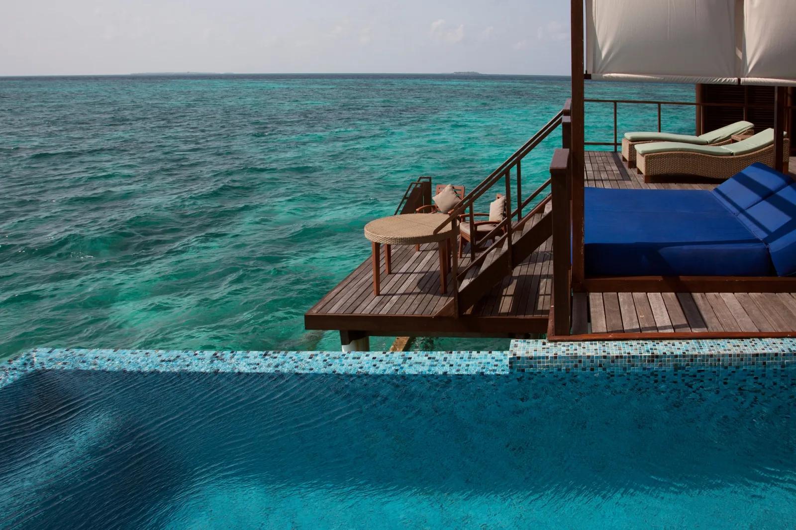 Overwater deck of a Coco Residence with Pool, mosaic-tiled infinity pool edge and blue day beds