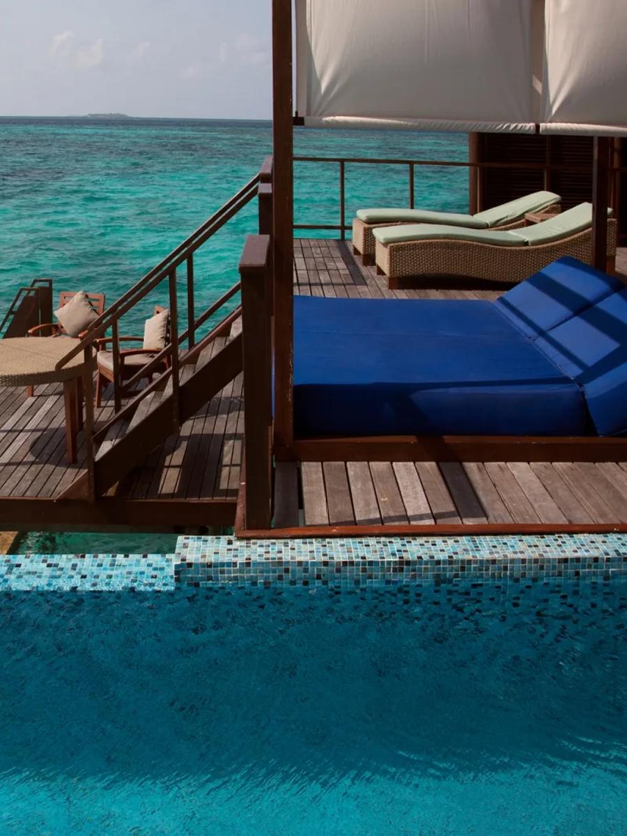 Overwater deck of a Coco Residence with Pool, mosaic-tiled infinity pool edge and blue day beds