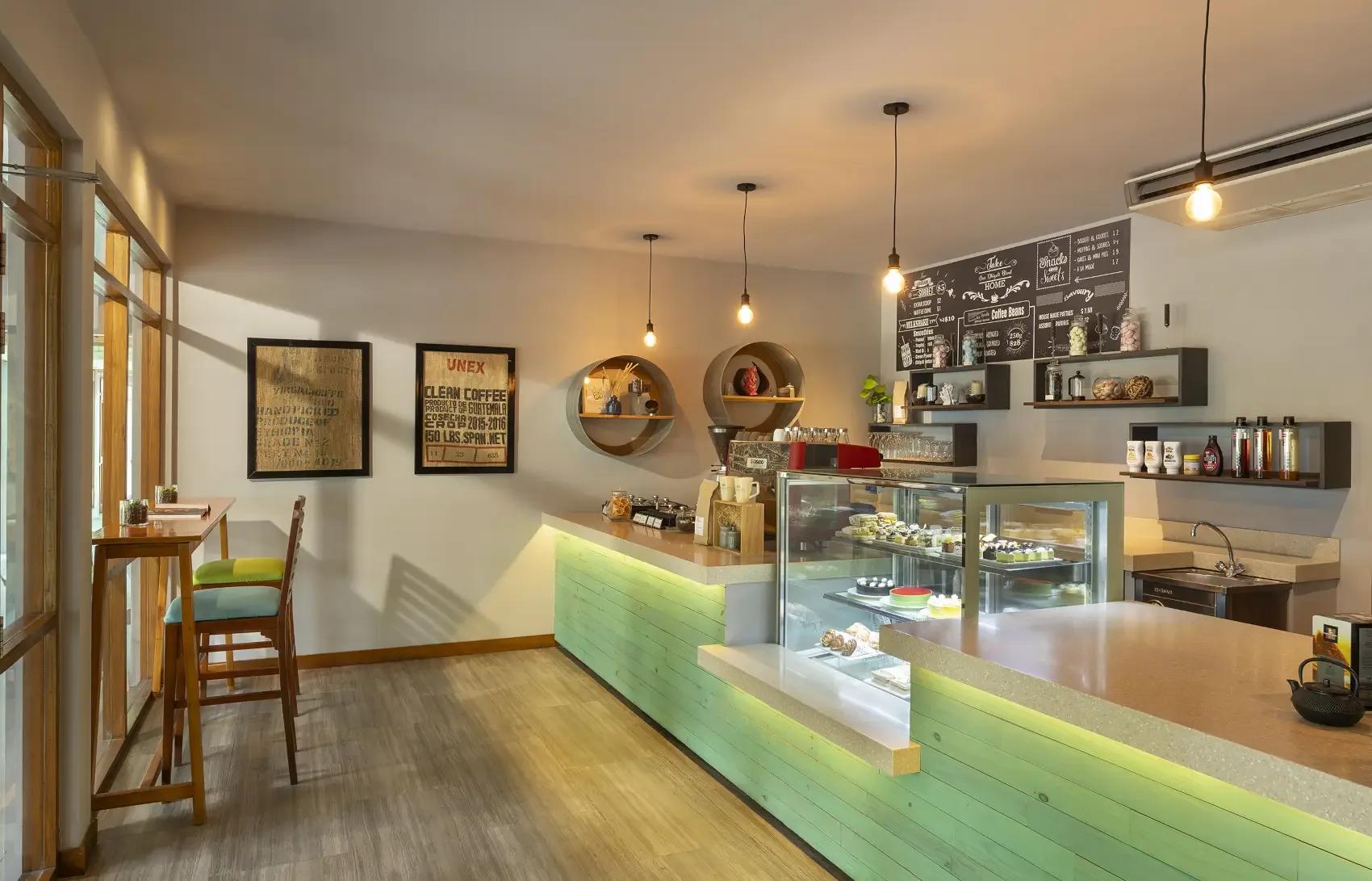 The counter and pastry display at Niva Dhigali's Café, pendant lights above a green-panelled bar