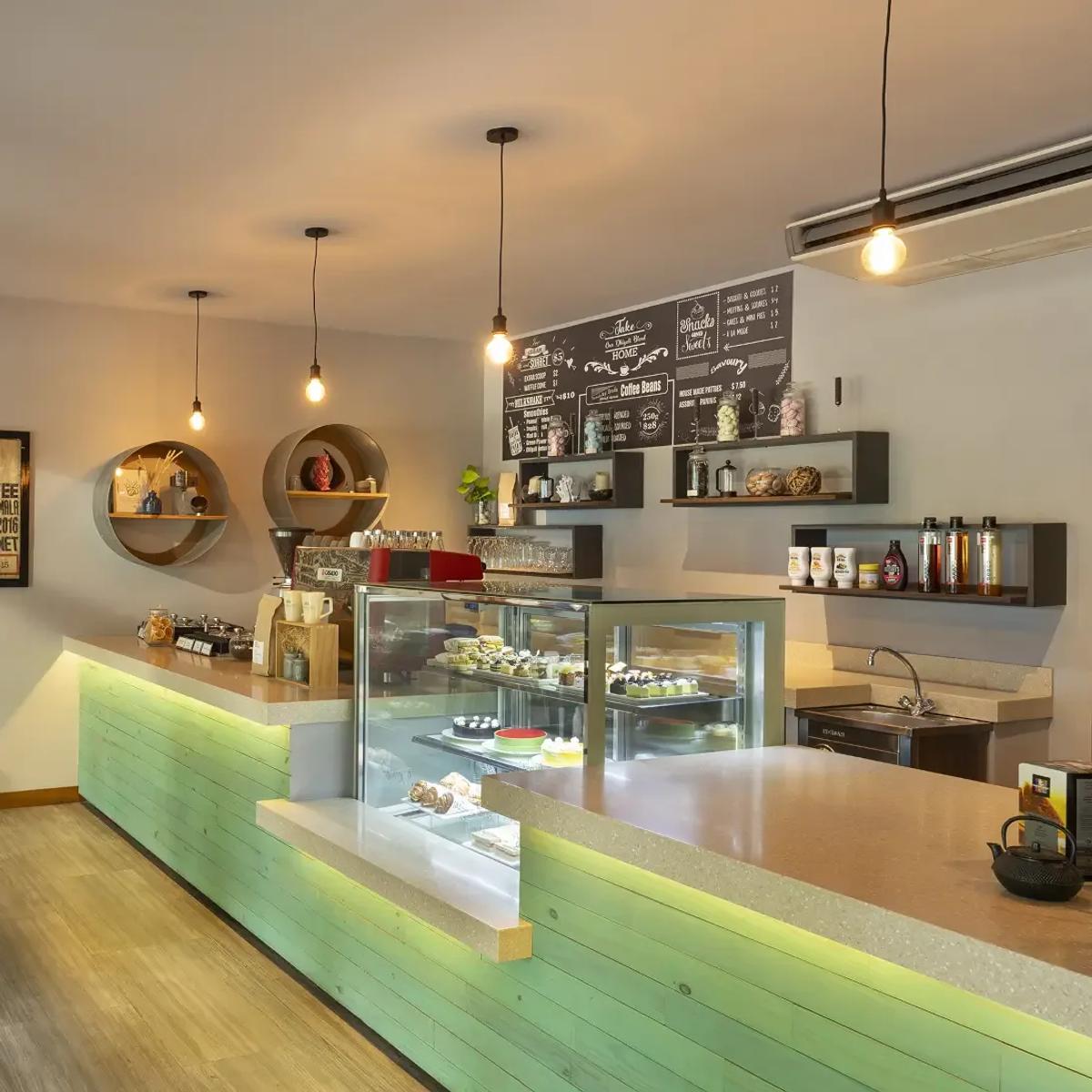 The counter and pastry display at Niva Dhigali's Café, pendant lights above a green-panelled bar