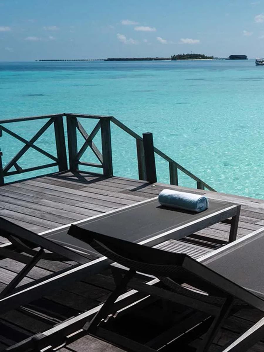 The deck of a Jacuzzi Water Villa, sun loungers facing an open lagoon view toward the horizon