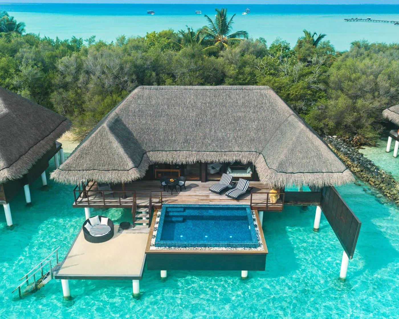 An aerial view of a One Bedroom Sunrise Overwater Suite with Pool, a guest relaxing on a lounger beside its private pool