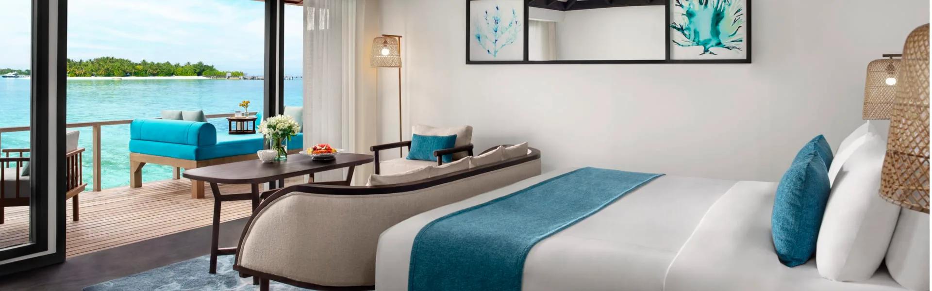 Superior Over Water Villa bedroom with a daybed deck looking across the open lagoon
