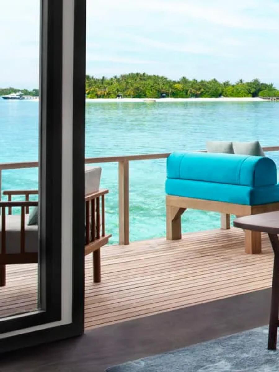 Superior Over Water Villa bedroom with a daybed deck looking across the open lagoon