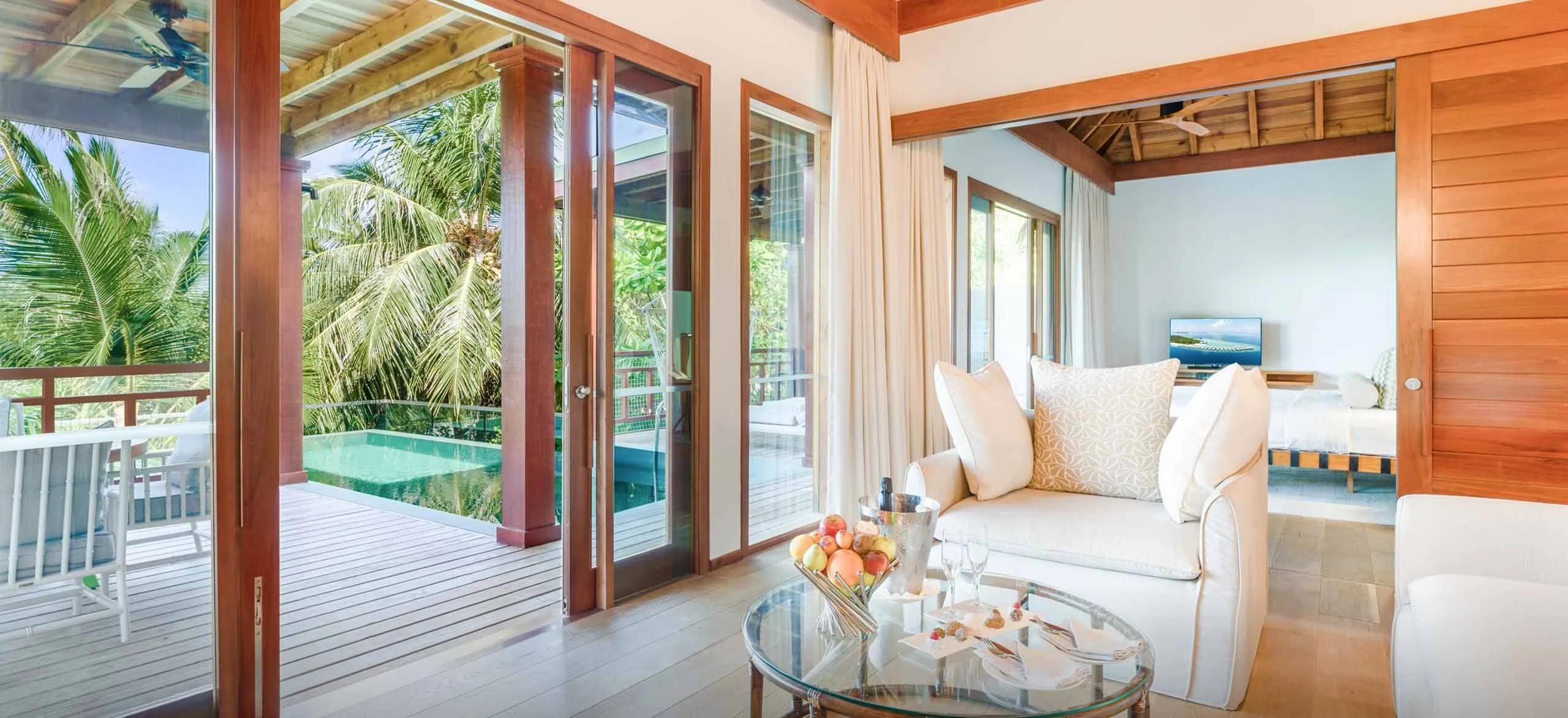 The living area of a Two-Bedroom Treetop Pool Villa at Amilla, opening onto its private pool set among the palms